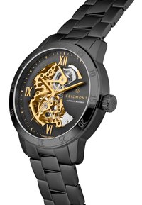 Automatisk klokke med svart metallhus og -rem, gjennomsiktig urskive som avslører gullmekanismen, og romerske tall som timeindikatorer.