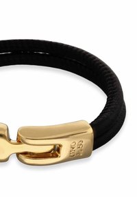 Coletero de tela negra con un cierre en tono dorado. El coletero tiene una textura suave y un diseño elegante y minimalista.