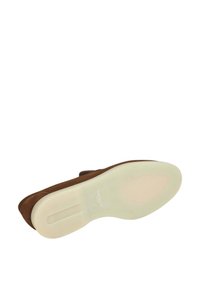 Scarpa in suede marrone con una suola piatta e liscia. La suola è di colore crema con un marchio sottile. Il design presenta una punta arrotondata e una forma minimalista.