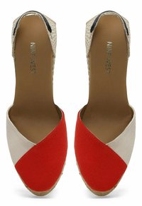 Espadrilles en toile rouge et beige avec un talon tissé, présentant un design en V et un dessus texturé. Semelle plate d'espadrille.