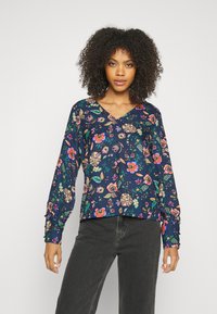 Blusa de manga longa azul-marinho com padrão floral em rosa, amarelo e verde; decote em V e punhos de manga franzidos; tecido leve.