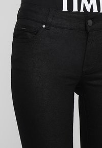 Svarta jeans i denim med en tajt passform, som har en framficka, en liten metallknapp och en subtil textur.