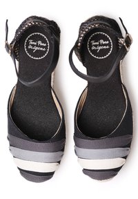 Espadrilles de lona negra con tiras de tela multicolor en negro, gris y crema. Presentan una correa en el tobillo y una suela texturizada.