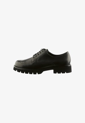 Zwarte leren veterschoen met een brogue-stijl, voorzien van geperforeerde details en een dikke, robuuste zool, zijaanzicht op een witte achtergrond.