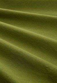 Tissu en coton vert olive avec une surface lisse et légèrement texturée, présentant des plis doux, mettant en valeur un fini mat et un éclat subtil.