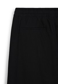 Schwarze Hose aus weichem Stoff mit elastischem Bund. Verfügt über eine einzelne Gesäßtasche und eine glatte Textur.