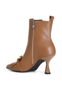 Hnědá kožená kotníková bota s špičatou špičkou, bočním zipem, dekorativní mašlí a štíhlým podpatkem. Hladká textura s elegantním designem.