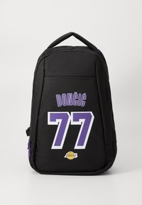 Fekete hátizsák lila részletekkel, amelyen a "DONČIĆ" név és a "77" szám vastag fehér betűkkel van nyomtatva. Az oldalon Lakers-logo található.