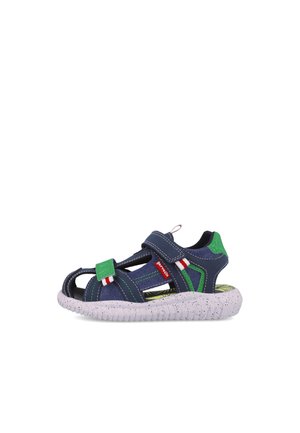 Sandalia infantil azul marino con acentos en verde y blanco. Presenta un diseño abierto, correa de velcro y suela blanca salpicada.