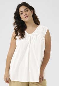 White sleeveless top with a V-neck and gathered detail on the shoulders. Made from a lightweight fabric with a loose, flowing fit.