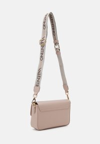 Gaiši rozā ādas plecu soma ar atloku, zelta krāsas aksesuāriem un regulējamu siksnu ar logo rakstu. Taisnstūra forma.