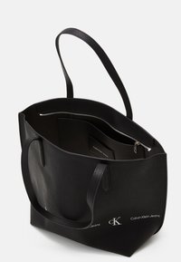 Czarna skórzana torba tote o strukturalnej fakturze, otwarta u góry, z kieszenią na zamek. Posiada dwie solidne rączki. Logo umieszczone z przodu.