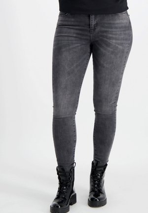 Strakke grijze denim jeans met een licht vervaagd textuur, voorzien van vijf zakken en een ritssluiting, gecombineerd met zwarte veterschoenen in een militaire stijl.