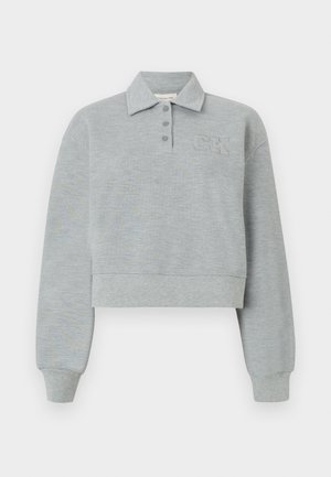 Sweat-shirt court gris clair à manches longues avec col, trois boutons, poignets côtelés et logo "CK" embossé sur le côté gauche de la poitrine.