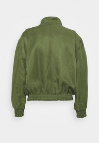 Veste bomber vert olive, avec un col montant, des poignets et un ourlet élastiqués, et une texture de tissu lisse et légèrement brillante.