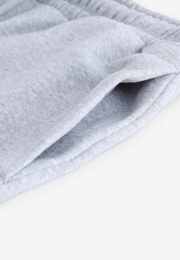 Graue Baumwollshorts mit einer weichen Textur, elastischem Bund und seitlichen Taschenöffnungen. Der Stoff erscheint bequem und lässig.