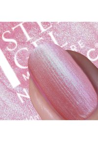 Lichtroze nagellak met een glinsterende, iriserende afwerking, weergegeven op een vinger met een gladde textuur, tegen een sprankelende roze achtergrond.