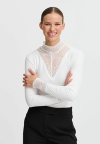 Hvid langærmet skjorte med blonderkrave og blondeaccenter på ærmerne, der har en ribbet tekstur og en slim fit.