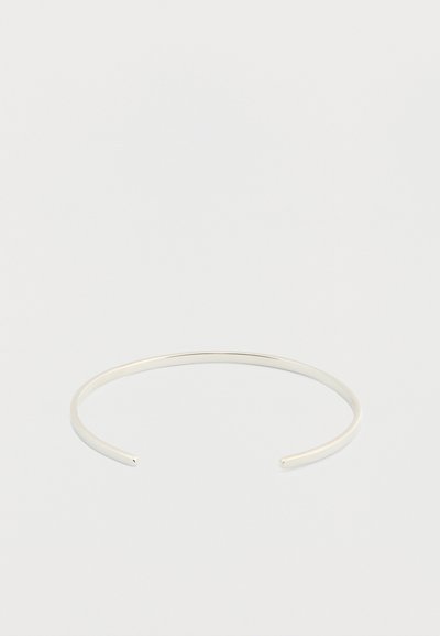 Λεπτό ανοιχτό βραχιόλι μανσέτα από ασημί μέταλλο με λεία, γυαλιστερή επιφάνεια σε απλό λευκό φόντο.