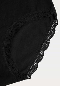 Svart bomullsunderkläder med en delikat spetsdetalj längs kanterna. Tyget är mjukt, med en slät textur och en sömlös design.