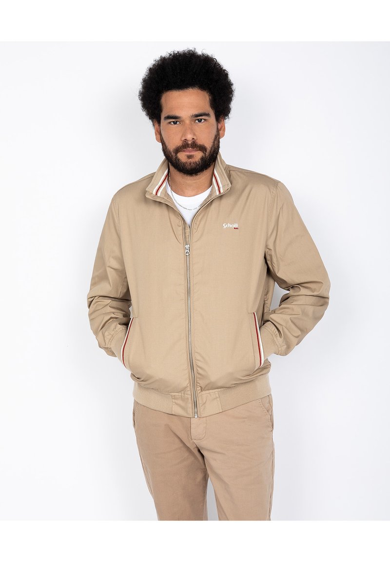 Veste légère beige avec un col montant, fermeture éclair à l'avant et un accent rayé le long du col et des poches. Design décontracté, texture lisse.