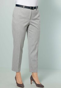 Pantaloni grigi chiari su misura con una sottile texture, lunghezza cropped e una cintura blu scuro. Abbinati a scarpe con tacco grigie.