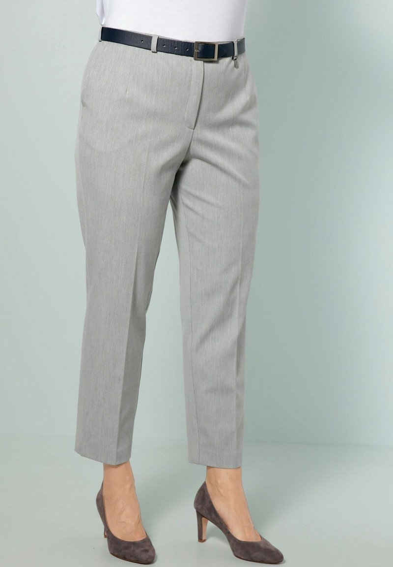 Pantaloni grigi chiari su misura con una sottile texture, lunghezza cropped e una cintura blu scuro. Abbinati a scarpe con tacco grigie.