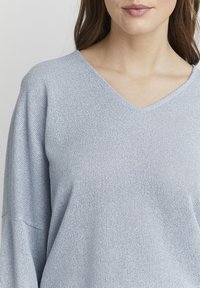 Maglione azzurro chiaro a V realizzato in tessuto a maglia testurizzato, con maniche larghe e vestibilità comoda, adatto per un abbigliamento casual.