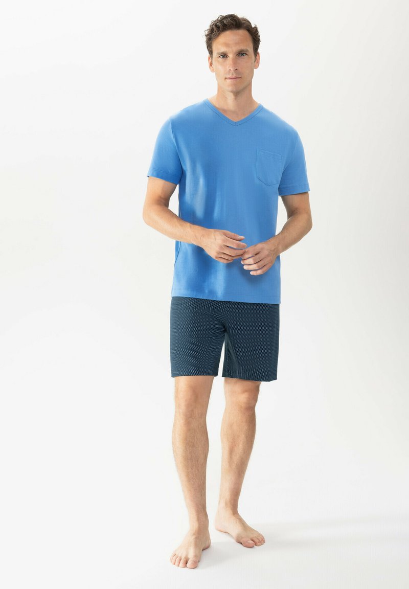 Light blue short-sleeve V-neck T-shirt with a chest pocket paired with dark navy shorts featuring a small white polka dot pattern.