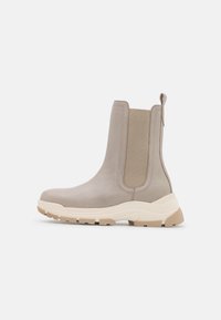 Beige Leder-Stiefeletten mit elastischen Seitenteilen und einer klobigen Sohle. Mit einer Schlaufe an der Rückseite und einer strukturierten Außensohle.