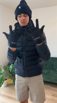 Svarte hansker med tettsittende passform, laget av et elastisk materiale. Brukes av en person i en svart dunjakke og en svart lue.
