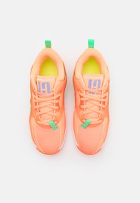 Oransje atletiske joggesko med mesh-stoff, grønne detaljer og rosa merkevare. Har snøring, polstret krage og en teksturert såle.