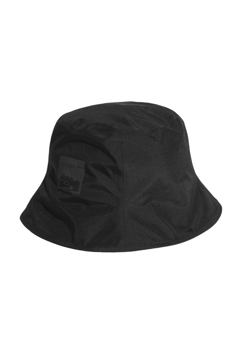 Melns buks ar plakanu vainagu, izgatavots no gludas auduma, ar plašu, uz leju slīpo malām. Iekļauts reljefs logotipa uzlīme sānos.