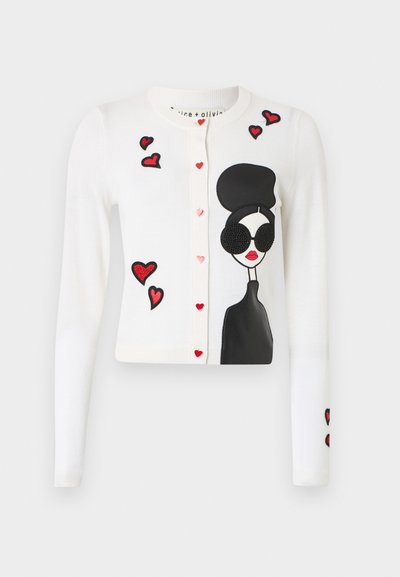 Fehér kardigán, fekete és piros hímzett szív- és alakmintákkal, rózsaszín szív alakú gombokkal és puha tapintással.