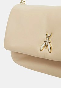 Borsa a mano in pelle beige con finitura testurizzata, caratterizzata da un accento dorato a forma di insetto sulla parte frontale. Include una tracolla a catena per il trasporto.