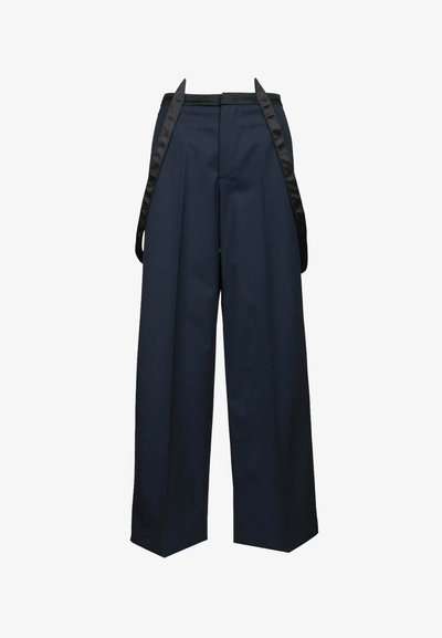 Pantaloni a gamba larga blu navy con bretelle di raso nero che pendono davanti, tagliati a vita alta.