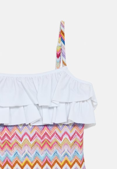 Μαγιό με λευκή κορυφή με βολάν και πολύχρωμο ζιγκ-ζαγκ σε αποχρώσεις ροζ, κίτρινου και μπλε. Ρυθμιζόμενες, διακοσμημένες τιράντες.