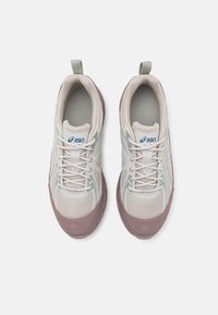 Sapatilhas ASICS em cinza claro e roxo suave, com tecido em malha, fecho de atacadores e uma sola texturizada com uma alça.