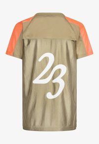 Koszulka sportowa z krótkim rękawem w kolorze złotym z pomarańczowymi akcentami. Posiada siateczkowy design oraz dużą białą cyfrę "23" na plecach. Gładka tekstura.