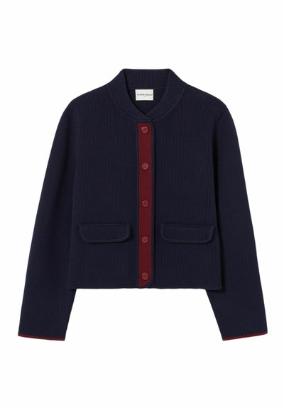 Cardigan ribbed navy con colletto rotondo, placca dei bottoni bordeaux e due tasche frontali. Presenta un bordo rosso a contrasto lungo l'orlo.