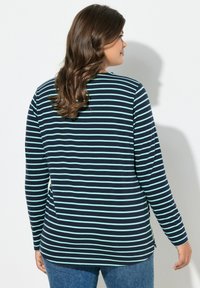 Dlouhý rukáv navy modrý top s světle modrými pruhy, bočními rozparky, měkkou látkou a volným střihem. Kombinováno s modrými džínami.