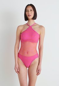 Jednodílné plavky s halter krkem, živé růžovo-oranžové cik-cak vzory a texturovaný síťovaný materiál.