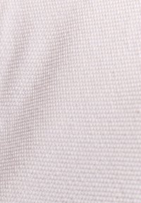 Licht beige textiel met een gestructureerde stof die een fijn weefpatroon toont. Het oppervlak lijkt glad met subtiele variaties in kleurintensiteit.