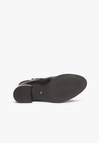 Bottine en cuir marron avec une surface texturée, un bout arrondi et un talon empilé bas. La semelle présente un motif nervuré pour une meilleure adhérence.