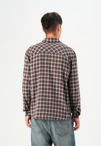 Brown and white plaid flannel shirt with button closure, long sleeves, and a relaxed fit. Material appears soft with a smooth texture.
