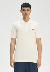 Polo bianco in tessuto strutturato, maniche corte e chiusura a tre bottoni. Presenta un piccolo logo ricamato rosso sul petto.