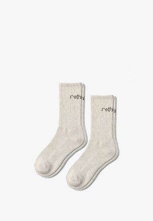 Chaussettes basses en coton de couleur gris clair, présentant un design côtelé et un texte imprimé "rethink" sur le bord. Texture douce et hauteur moyenne.