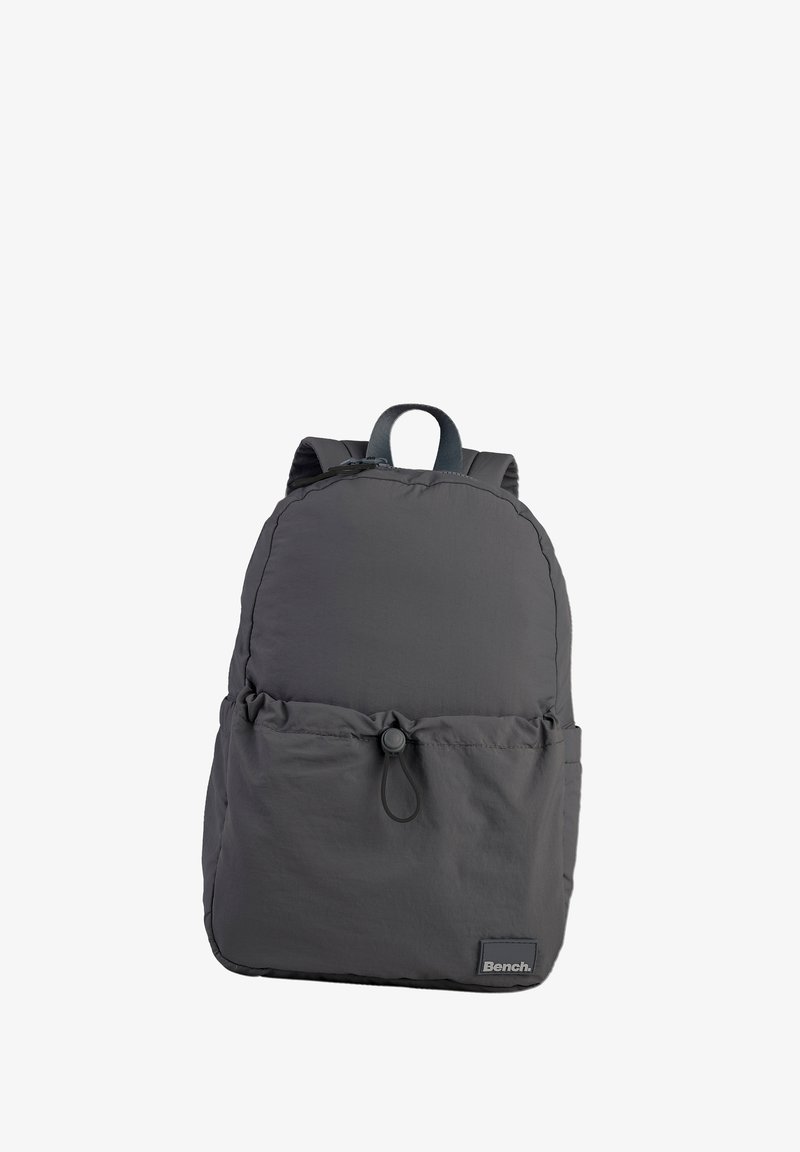 Gray nylon backpack with a rounded top, adjustable straps, front cinch pocket, and a rectangular base. Features a brand logo on the front.