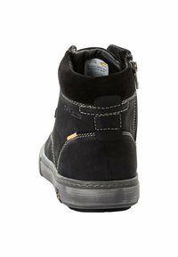 Zwarte enkellaarzen met een suede afwerking, verstevigde hak, grijze rubberen zool en een zijrits. Decoratieve stiksels en gele accentdetails.