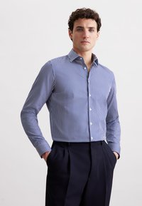 Camicia a maniche lunghe a righe blu e bianche con colletto classico. Presenta chiusura con bottoni e polsini a contrasto, realizzata in tessuto liscio.